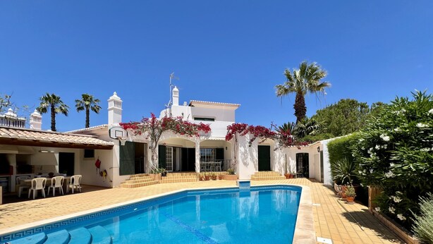 A swimming pool with a tiled deck, surrounded by potted plants and palm trees. - ALVOR TRADITIONAL VILLA WITH POOL by HOMING (Mexilhoeira da Carregação)