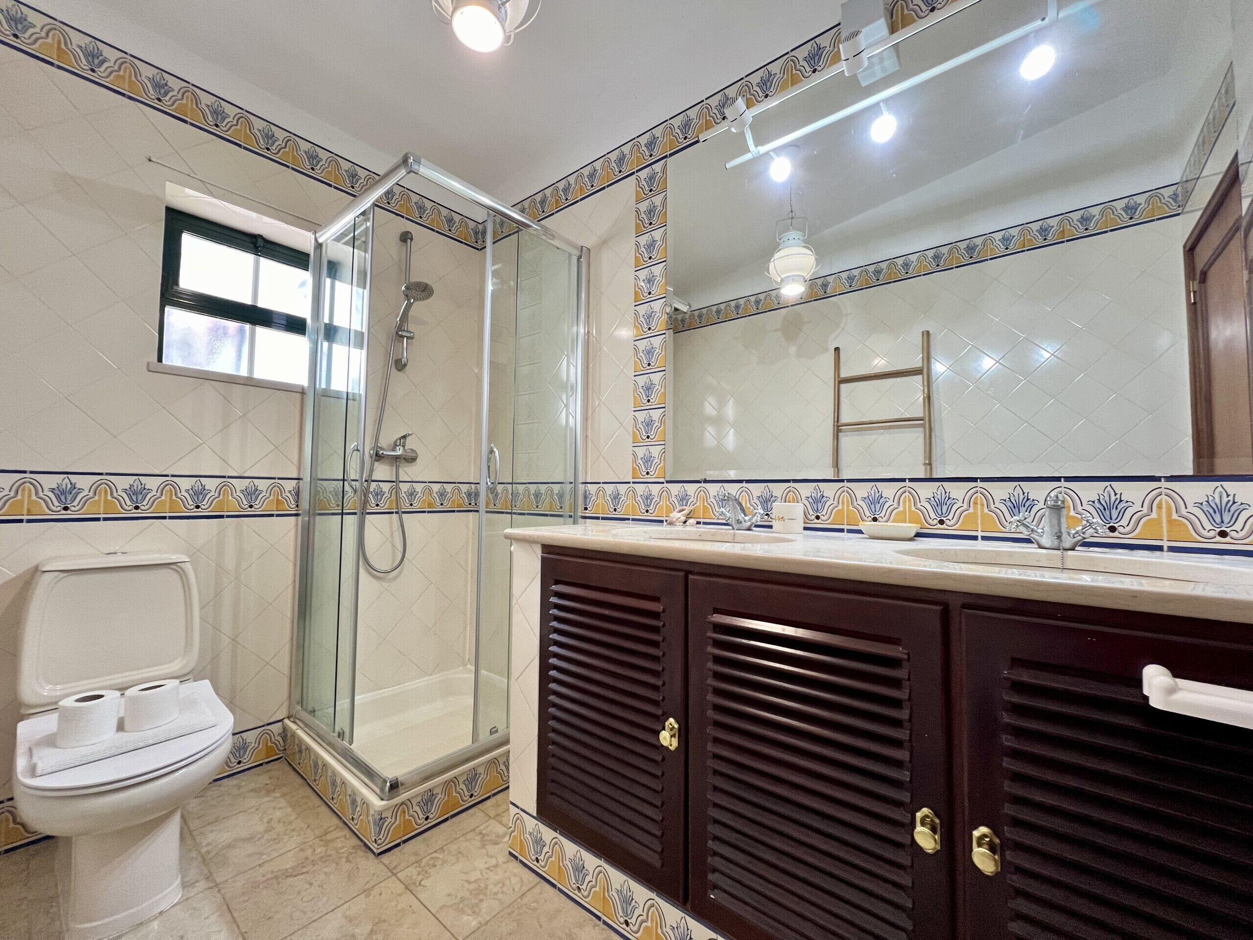 Une salle de bain avec une douche à parois de verre, des toilettes et un meuble-lavabo avec un miroir.