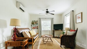 A living room with a sofa, a coffee table, a chair, a TV, and a ceiling fan.
