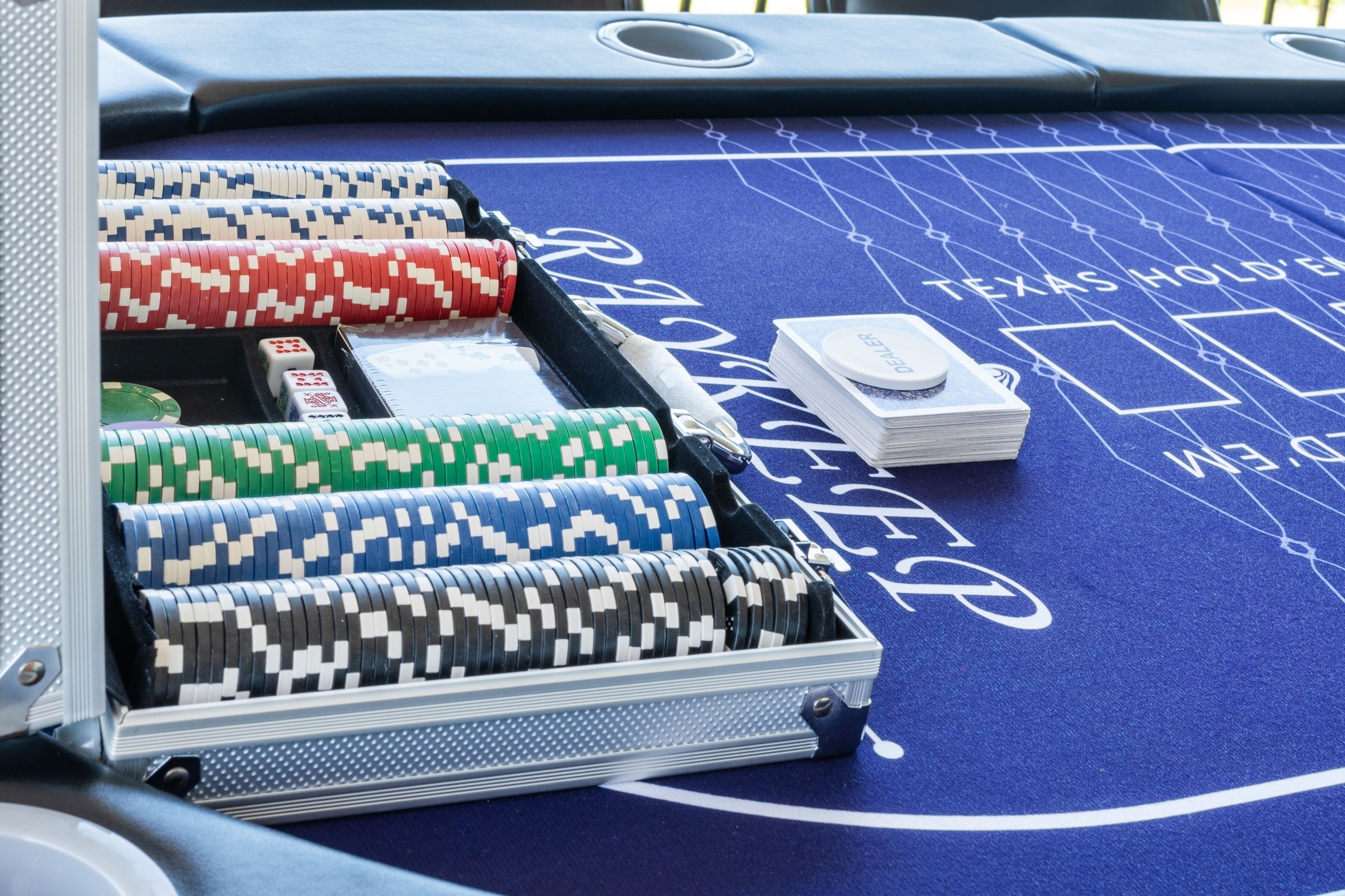 Ein Pokertisch mit Chips, Karten und einem Texas Hold’em Logo, bedeckt mit einem blauen Filz.