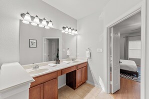 Ein Badezimmer mit einem Doppelwaschbecken, einem großen Spiegel und einer begehbaren Dusche.