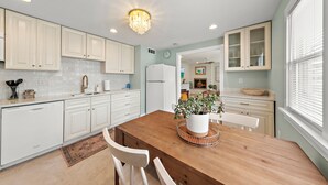 A modern kitchen with white cabinetry, a wooden dining table, and recessed ceiling lights. - Cozy Beach Haven Terrace Home, 1 Block From Beach, Restaurants & Wawa! (Long Beach)