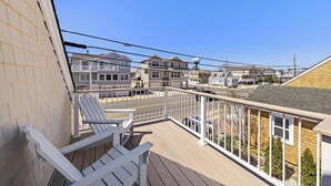 A balcony with white Adirondack chairs, a view of neighboring houses, and a clear blue sky. - Cozy Beach Haven Terrace Home, 1 Block From Beach, Restaurants & Wawa! (Long Beach)