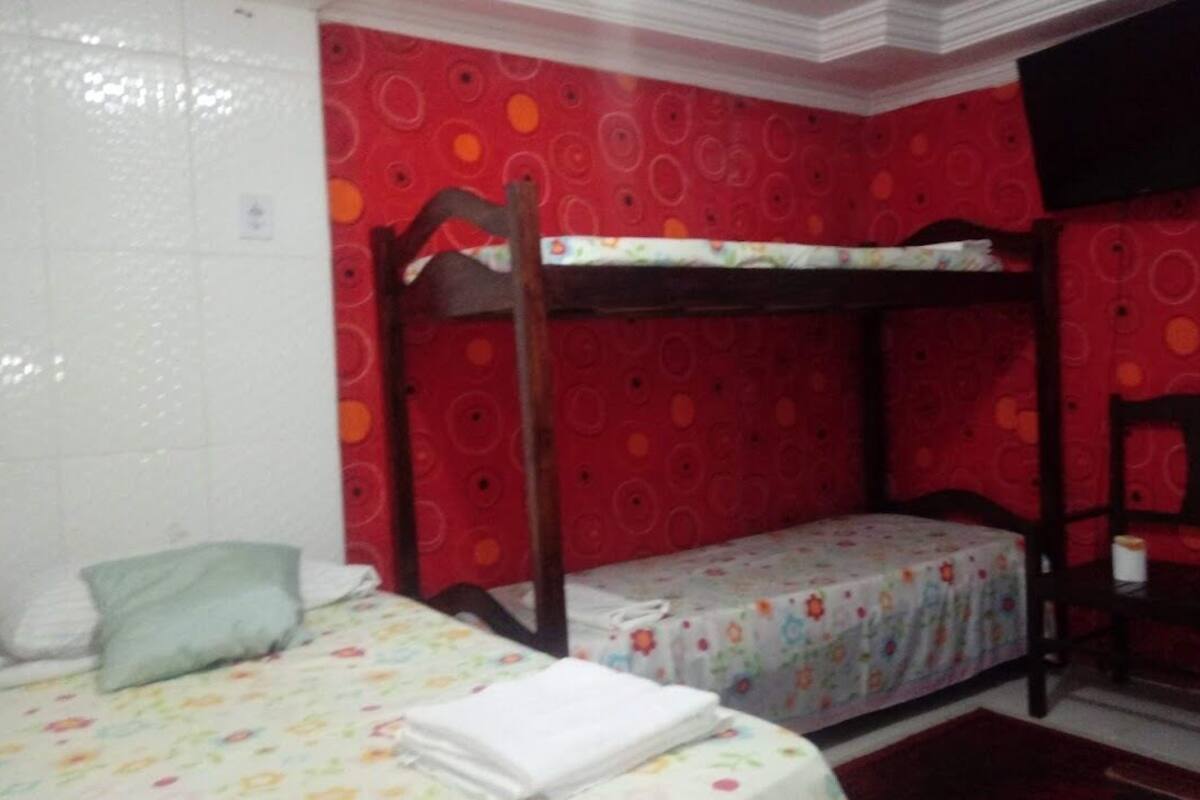 A room with bunk beds, a chair, and a television on the wall.