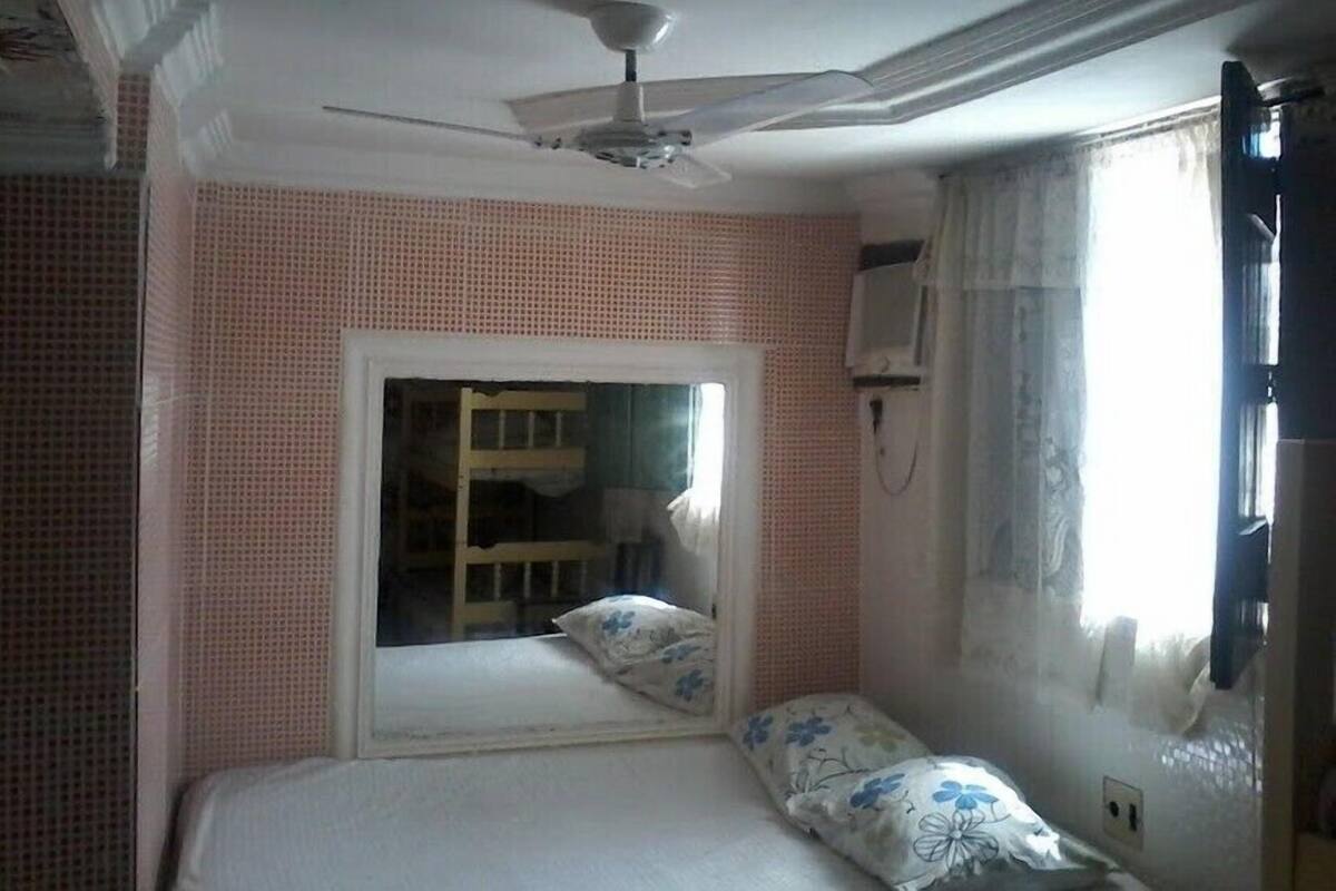 A bedroom with a single bed, a ceiling fan, a window with curtains, and a visible closet door.
