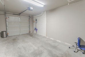 Spacious room with a large garage door, office chair, and modern lighting.