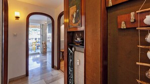 Un couloir avec des portes en bois, un radiateur et une étagère ornée d’objets décoratifs.