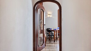 Un couloir mène à une salle à manger où se trouvent une table et des chaises.