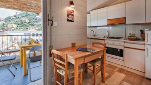 Une cuisine compacte avec un coin repas, une vue sur la ville et un balcon doté d’un espace salon extérieur.
