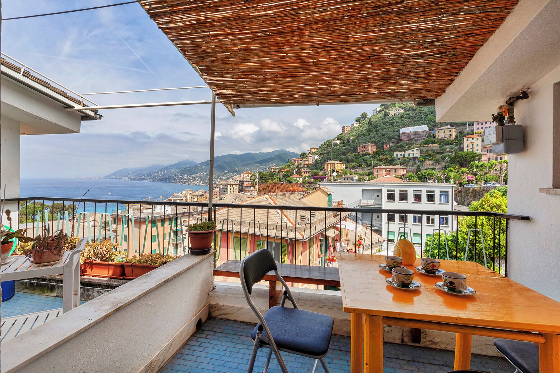 Un balcon avec vue sur la mer et sur une ville située sur une colline.