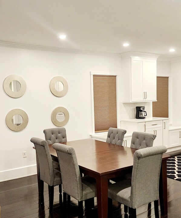 A dining area with a wooden table and four upholstered chairs, white cabinets, and decorative mirrors on the wall. - Comfort and Location! (Medford)