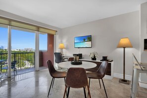 A modern hotel room with a balcony, a round dining table with chairs, a flat-screen TV, and two floor lamps. - Modern Bay View with Free Parking (Miami)