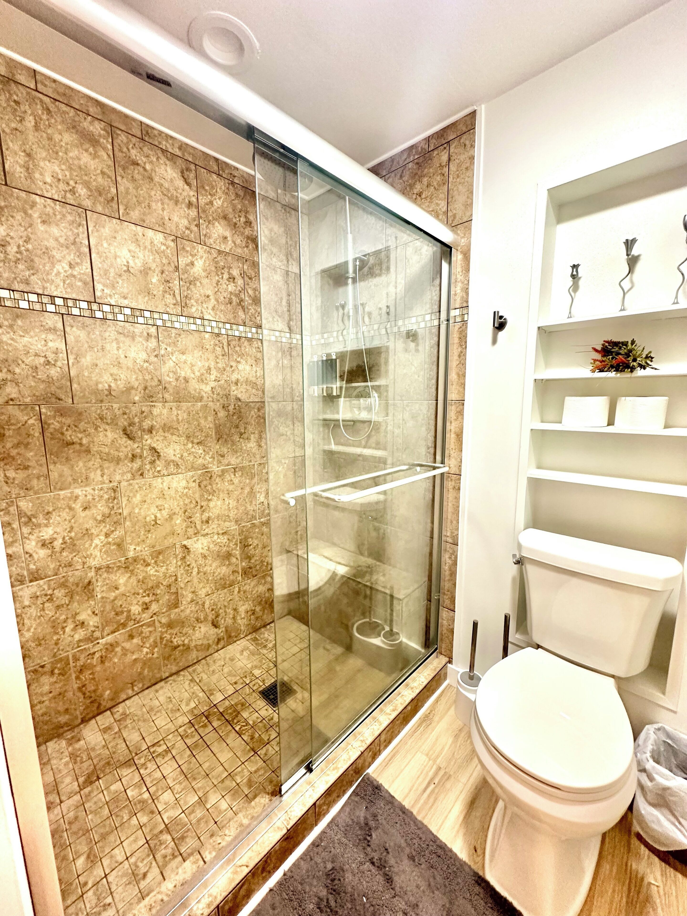 Ein Badezimmer mit einer Duschkabine, einer Toilette und einem Regal mit Dekoration.