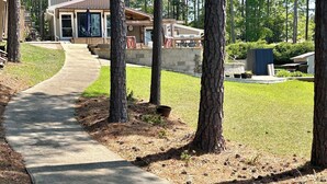 A residential area with a concrete pathway leading to a house with a large window and a door. - Sleeps 6, Inground Pool, Amazing Views + More! (Sparta)