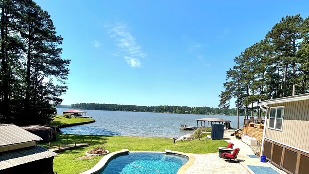 A backyard with a swimming pool, hot tub, and a dock extending into a lake. - Sleeps 6, Inground Pool, Amazing Views + More! (Sparta)