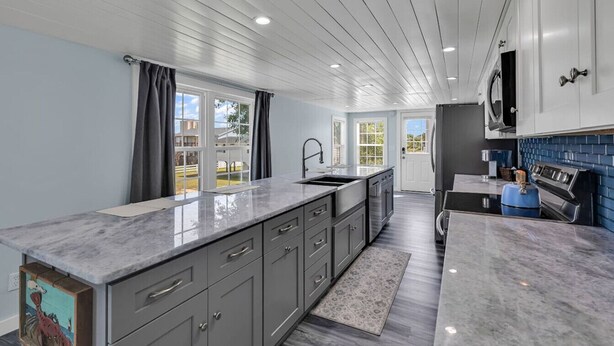 A modern kitchen with grey cabinets, a marble countertop, and a blue backsplash. - Blue Sky Ranch-walk to beach! Sleeps 6 (Murrells Inlet)