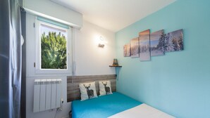 Ein Schlafzimmer mit einem Bett, einem Fenster, einer Heizung und einer Wand mit drei gerahmten Bildern.