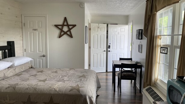 Une chambre à coucher comprenant un lit, un bureau, une chaise, un radiateur et une fenêtre avec des rideaux.