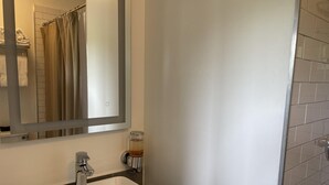 A bathroom with a white sink, a mirror, and a glass of amber liquid on the wall.