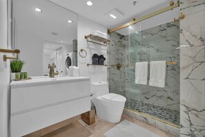 Un bagno moderno con doccia vetrata, sanitari bianchi e dettagli in marmo.