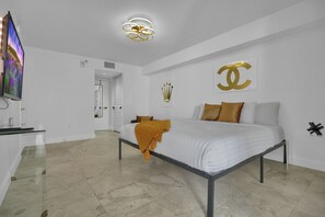 Una camera da letto moderna con un letto, una televisione e un lampadario.