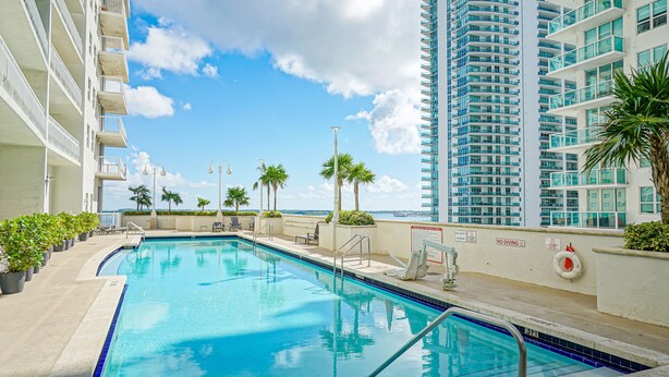 A swimming pool with a view of a tall building and palm trees. - Zeus Sanctuary in Brickell Miami (Miami)