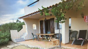 A house with a patio, a table, and chairs. There is a dog in the yard. - Home. (Zonza)