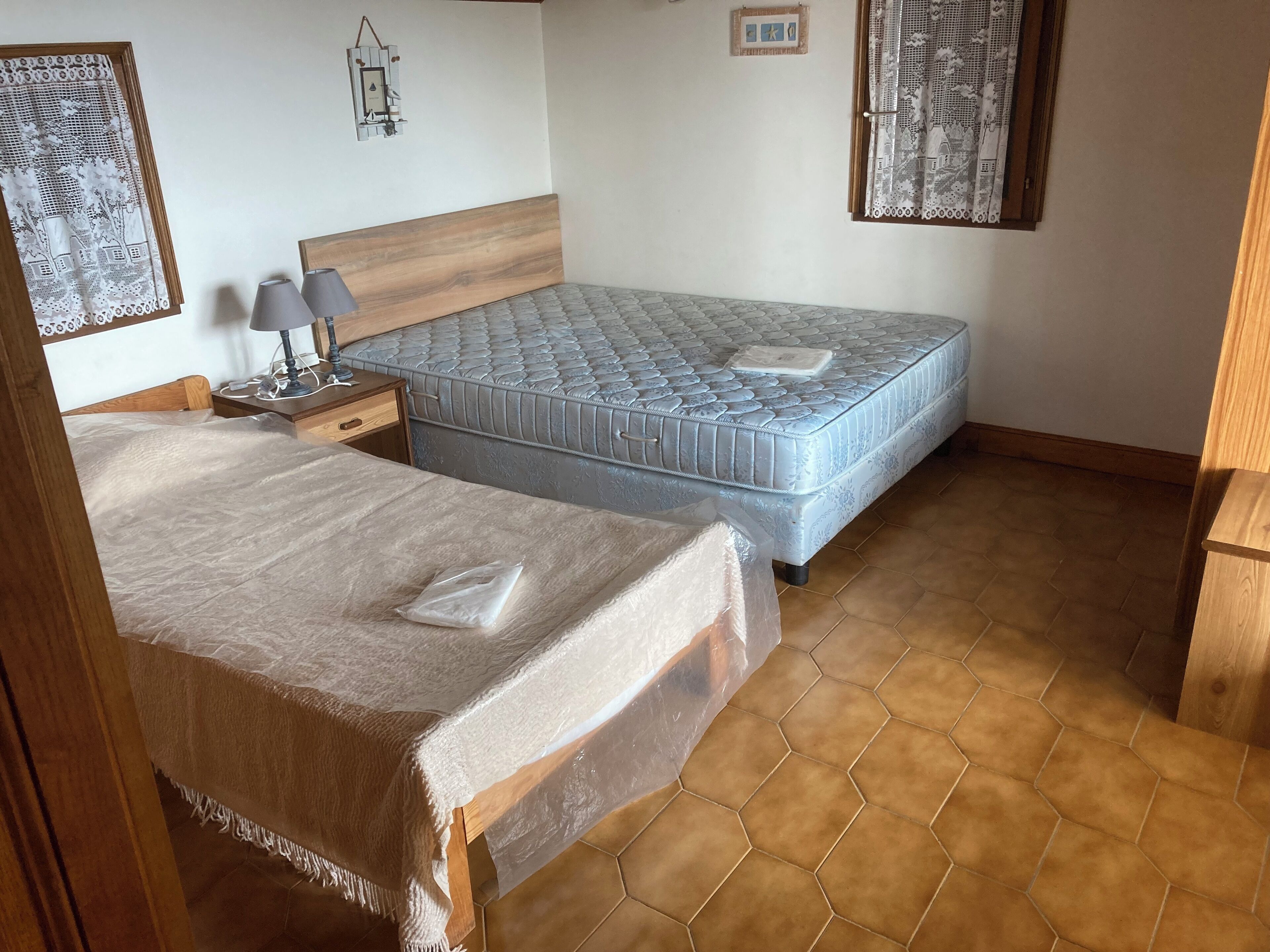 A bedroom with two beds, a nightstand with a lamp, and a wooden headboard.