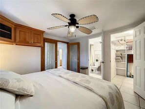 A bedroom with a bed, a ceiling fan, wooden cabinets, and a walk-in closet. - Kick back and Relax at Leisure Beach (Hudson)