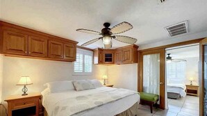 A bedroom with a bed, wooden cabinets, a ceiling fan, and a door leading to another room. - Kick back and Relax at Leisure Beach (Hudson)