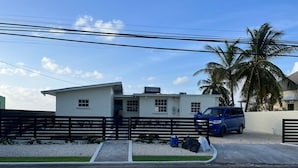 A white single-story house with a blue car parked in the driveway.