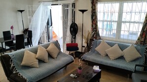 A living room with two sofas, a coffee table, and a dining area with chairs and a table.
