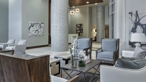 Een moderne lobby met zithoeken, een grote centrale pilaar en kunstwerken aan de wanden.