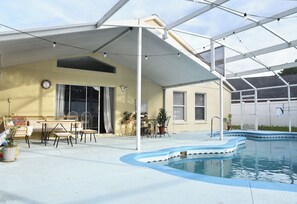 A covered outdoor area with a pool, seating, and potted plants. - Artisan Poolside Paradise near Disney (Clermont)