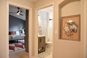 A hallway leading to a bedroom with a bed, a bathroom with a toilet and sink, and a framed artwork on the wall. - Artisan Poolside Paradise near Disney (Clermont)