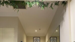 Ein Flur mit einer weißen Tür, einem gerahmten Bild von Sydney, einem Spiegel und einem kleinen Tisch mit einem Topfpflanzen.