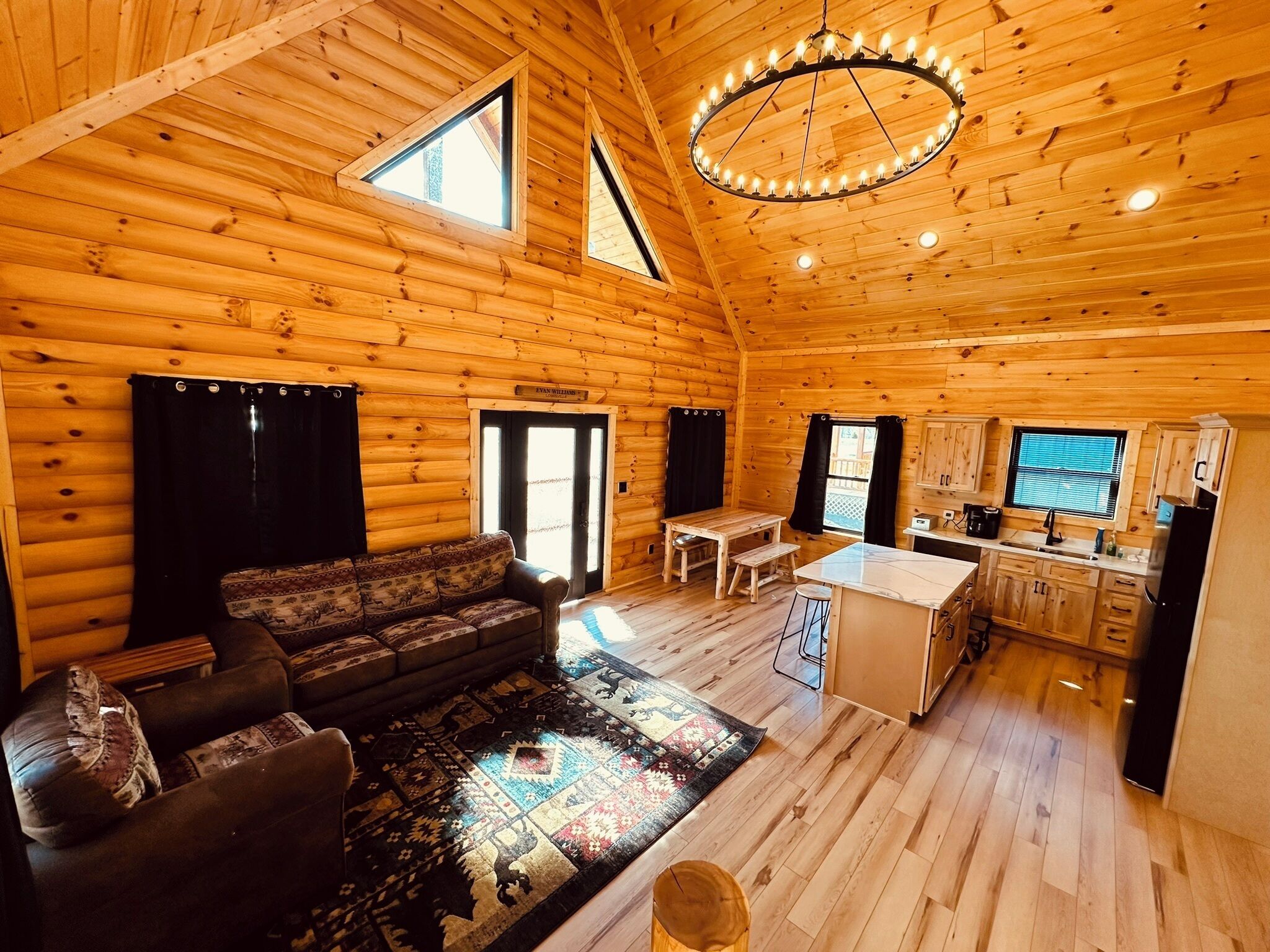 Acogedor interior de cabaña de madera con sala de estar, comedor y cocina.