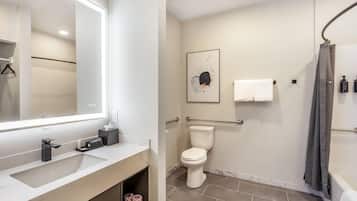 Un baño moderno con un espejo grande, un inodoro, una ducha y un lavabo.