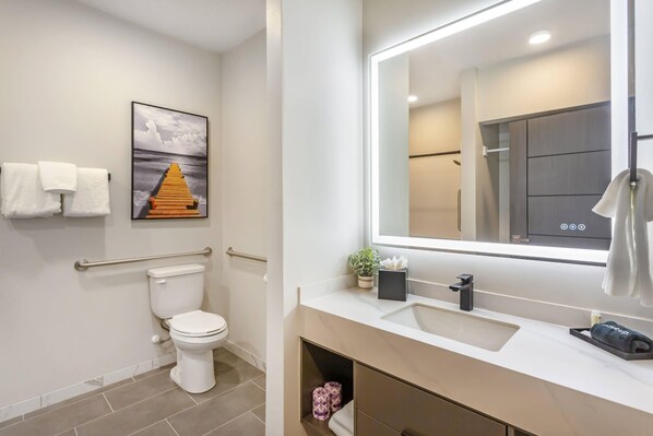 Une salle de bain moderne équipée de toilettes, d’un lavabo, d’un miroir et d’un porte-serviettes.