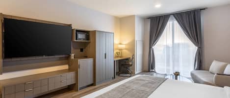 Una habitación de hotel moderna con una cama grande, un televisor de pantalla plana, un escritorio con una silla y un sofá.