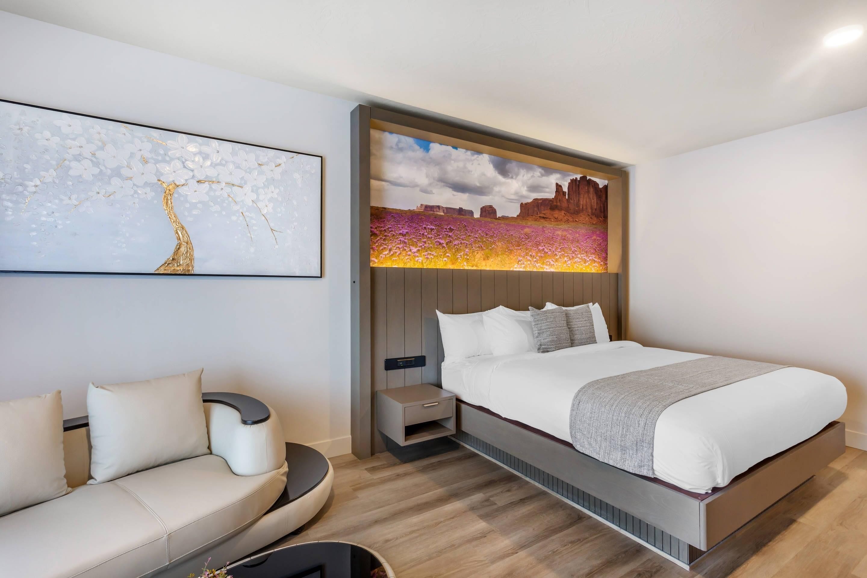 Un dormitorio moderno con cama, sofá y una obra de arte colgada en la pared.