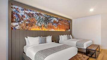 Habitación de hotel con dos camas, un mural grande en la pared y un banco de madera.