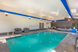Una piscina con borde azul, un jacuzzi y una zona de estar con cojines.