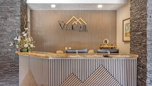 A reception desk with a wooden panel design, a logo above it, and a framed picture on the wall.