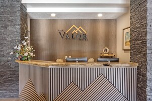 Un mostrador de recepción con diseño de panel de madera, un logotipo en la parte superior y una foto en el marco en la pared.