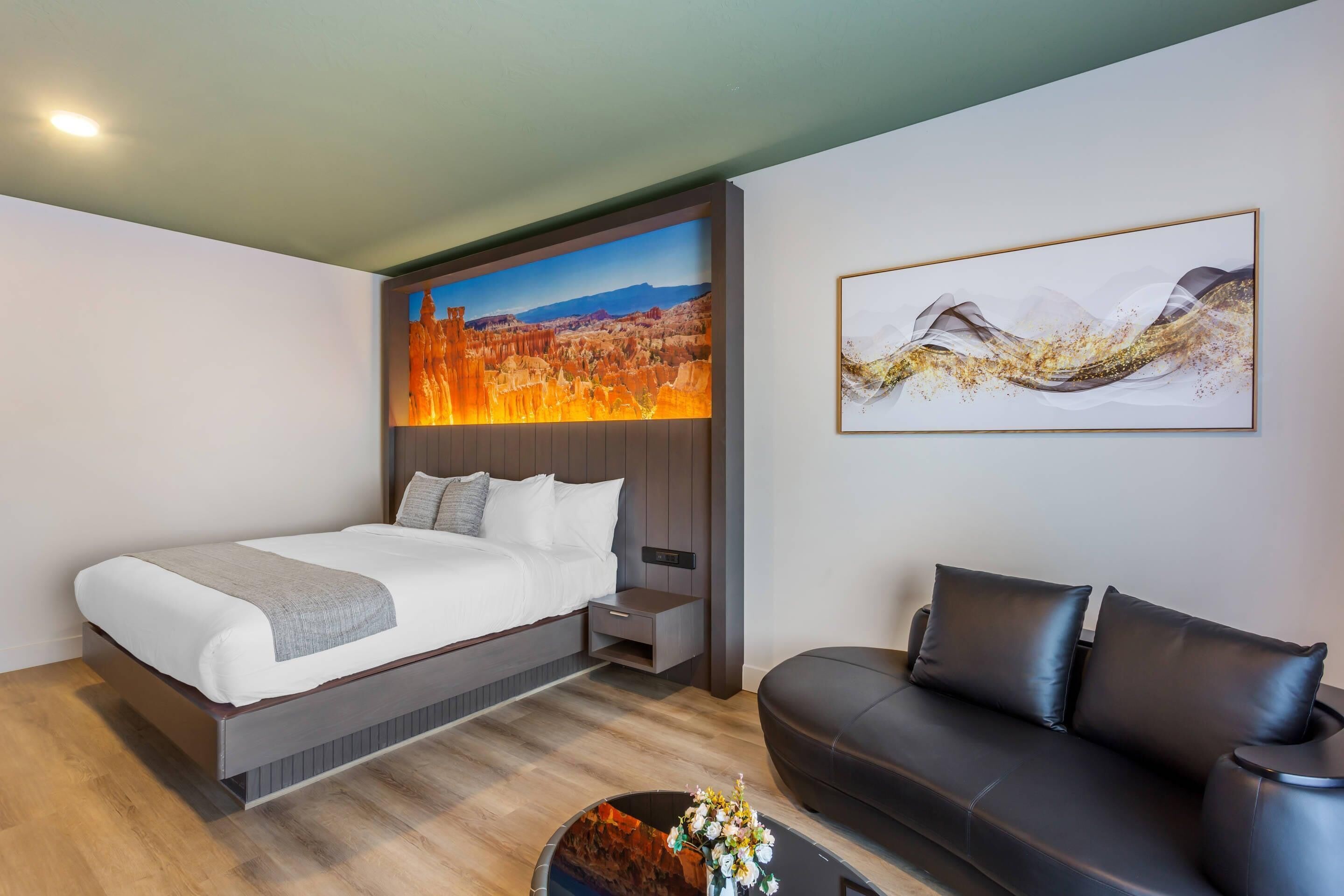 Una camera d'hotel moderna con un letto, una poltrona, una TV a parete e un quadro.
