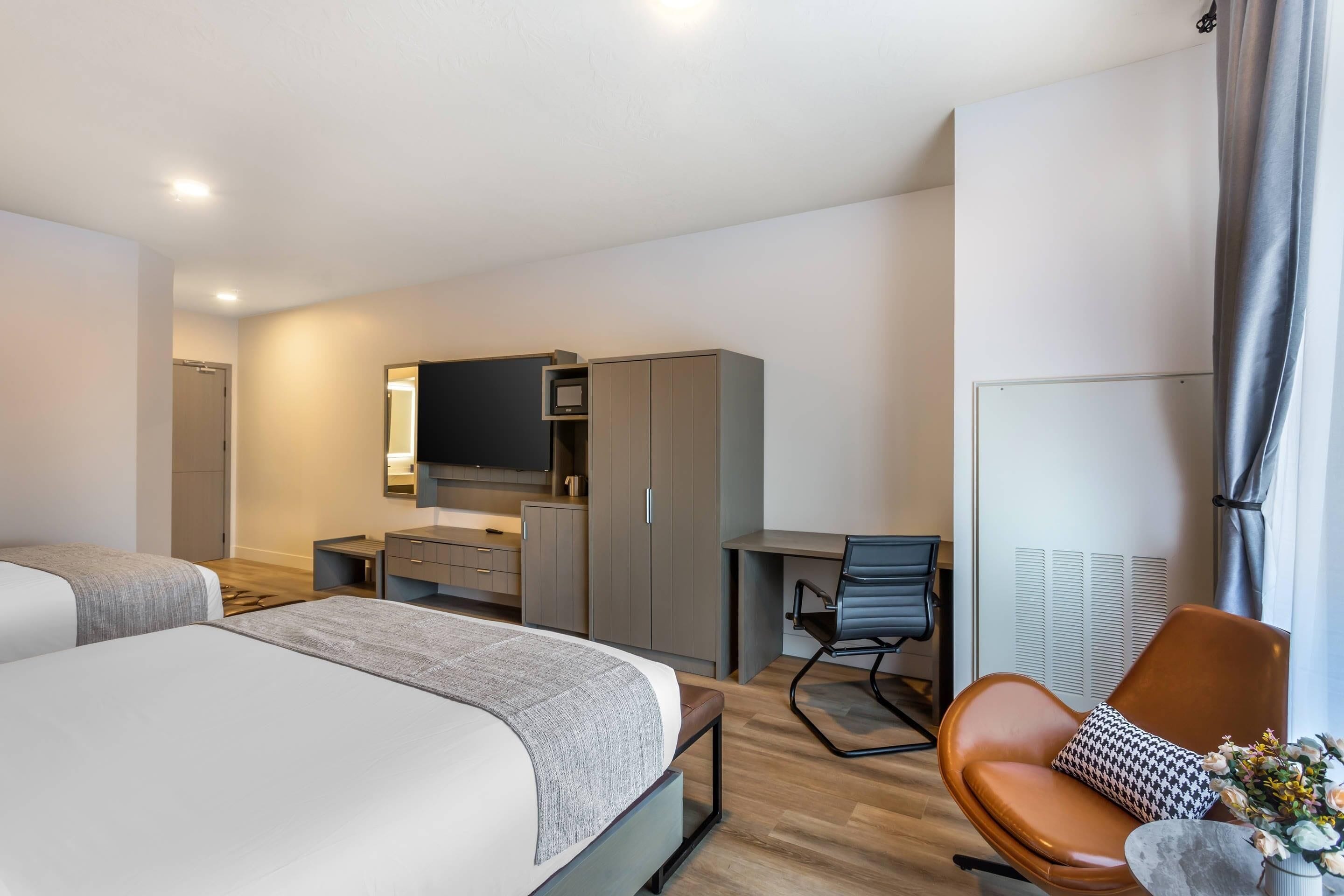 Une chambre d’hôtel moderne équipée d’un lit, d’un bureau, d’une chaise et d’un téléviseur.