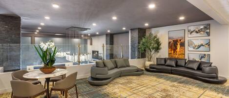 Una sala de estar moderna con un sofá modular, una mesa redonda de centro y un comedor con sillas.