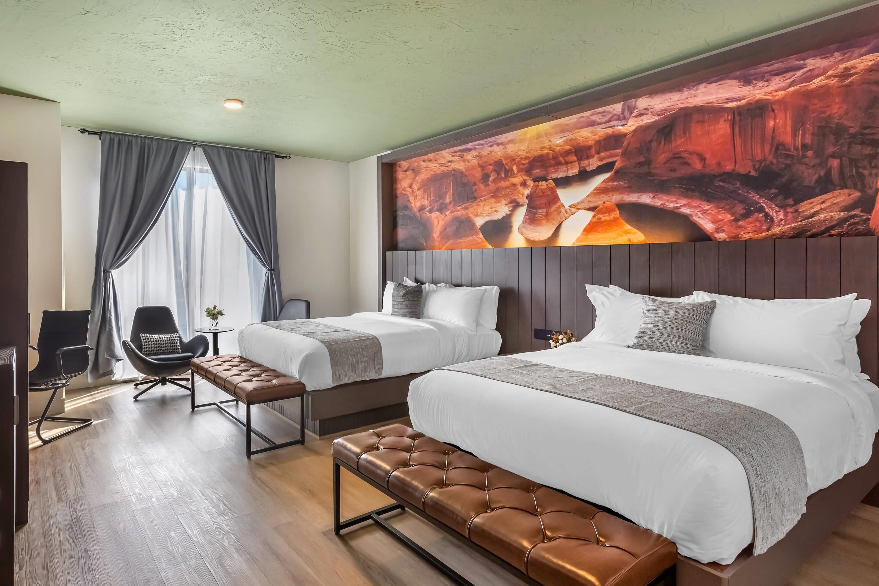 Une chambre d’hôtel avec deux lits, un banc, une chaise et une grande fresque murale.