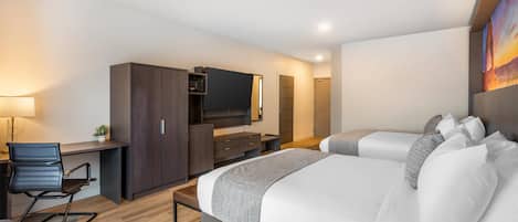 A modern hotel room with a large bed, a desk with a chair, a television, and a wardrobe.